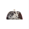 Jesalin Aluna clutch in natural cowhide with black, brown, and ivory print, featuring pink leather trim and gold frame.