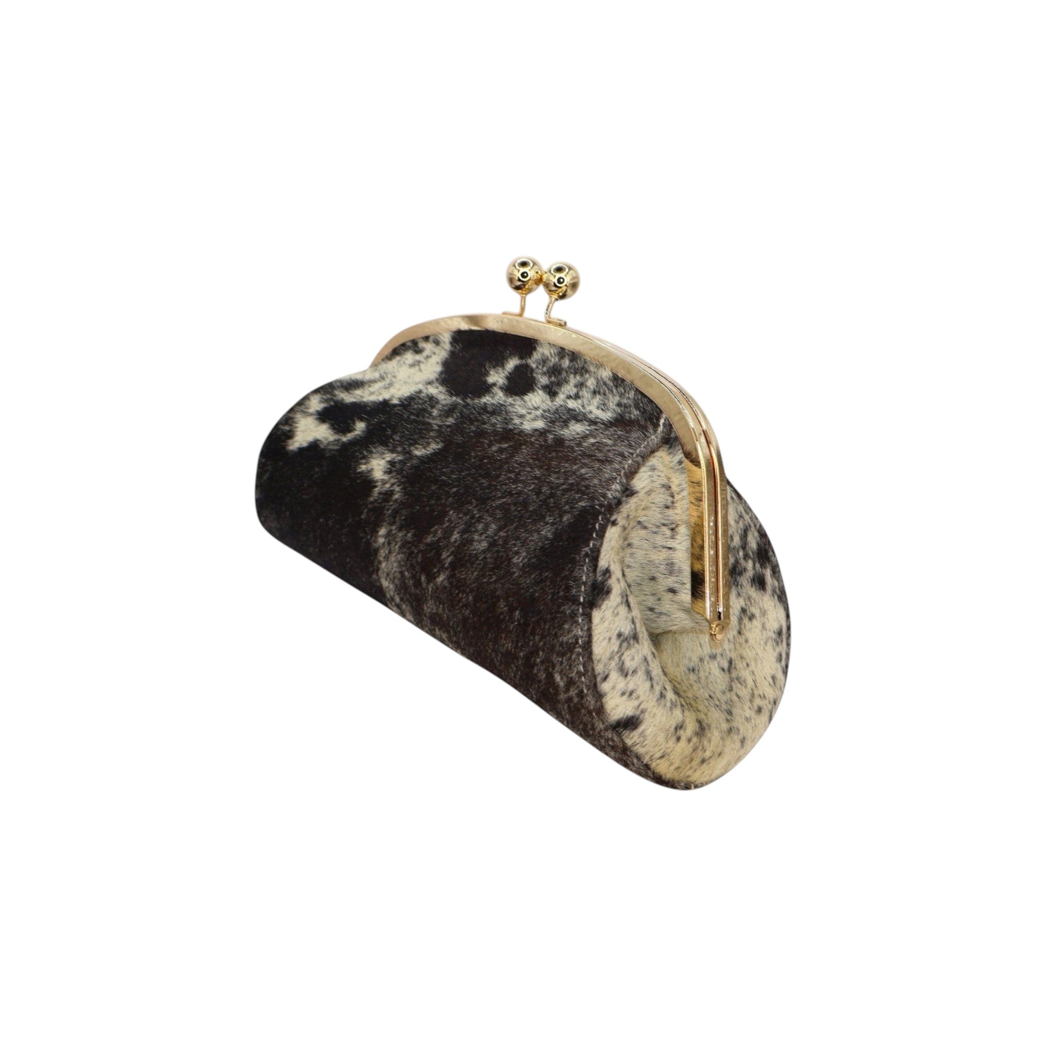 Jesalin Aluna clutch in black and white cow print leather with a gold kiss lock frame and rigid curved silhouette.