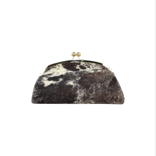 Jesalin Aluna rigid clutch bag in black and white cow print leather with a gold kiss lock frame.