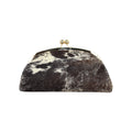 Clutch rígida Jesalin modelo Aluna en piel bovina con estampado de vaca, marco metálico dorado y cierre kiss lock.