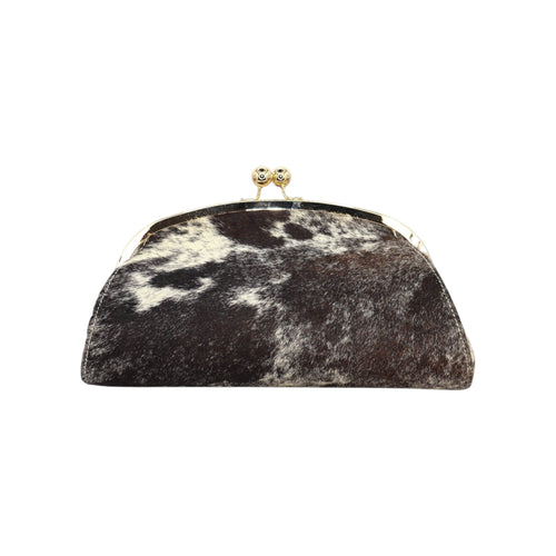 Clutch rígida Jesalin modelo Aluna en piel bovina con estampado de vaca, marco metálico dorado y cierre kiss lock.